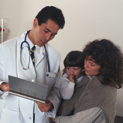 A doctor reviews a child's medical chart with its mother.