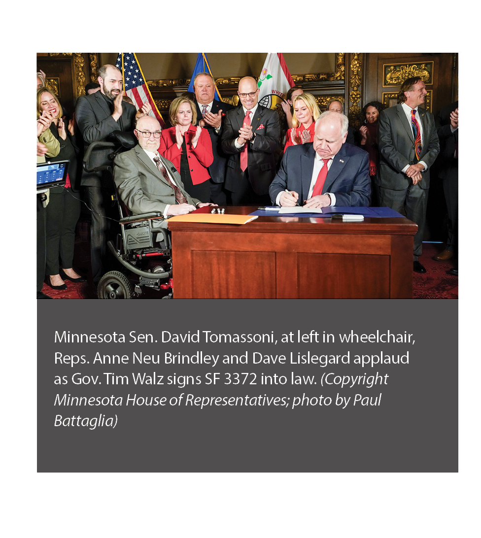 Photo of Minnesota Gov. Tim Walz signing SF 3372 as Sen. Dave Tomassoni looks on